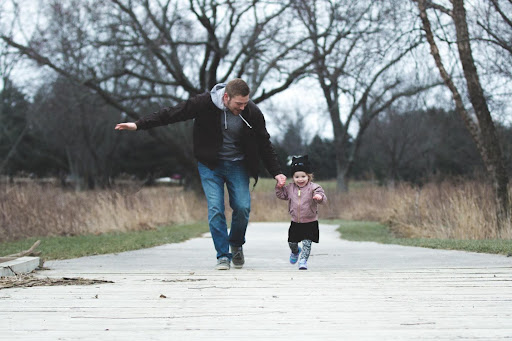 Child walking with man outside.