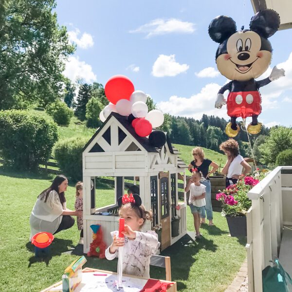 Mickey mouse birthday party with kids and adults outside.