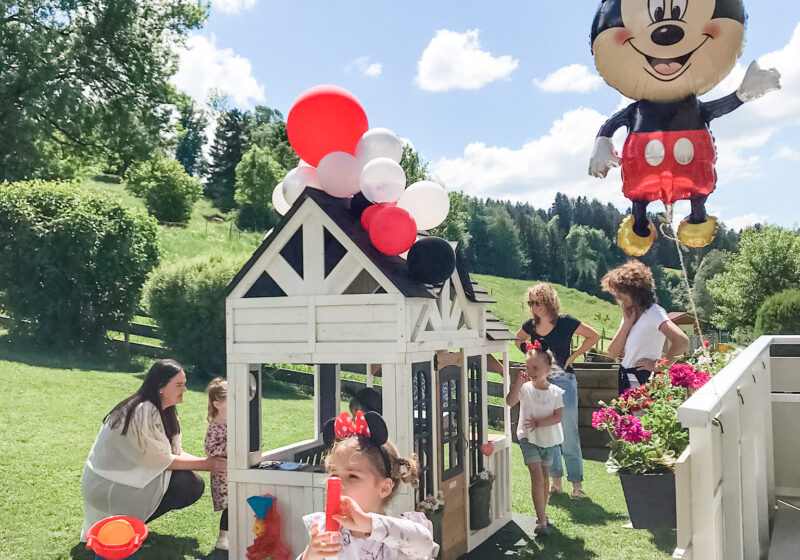 Mickey mouse birthday party with kids and adults outside.