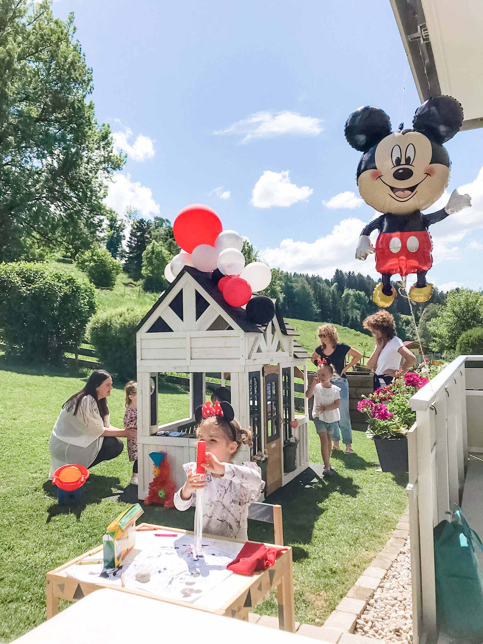 Mickey mouse birthday party with kids and adults outside.